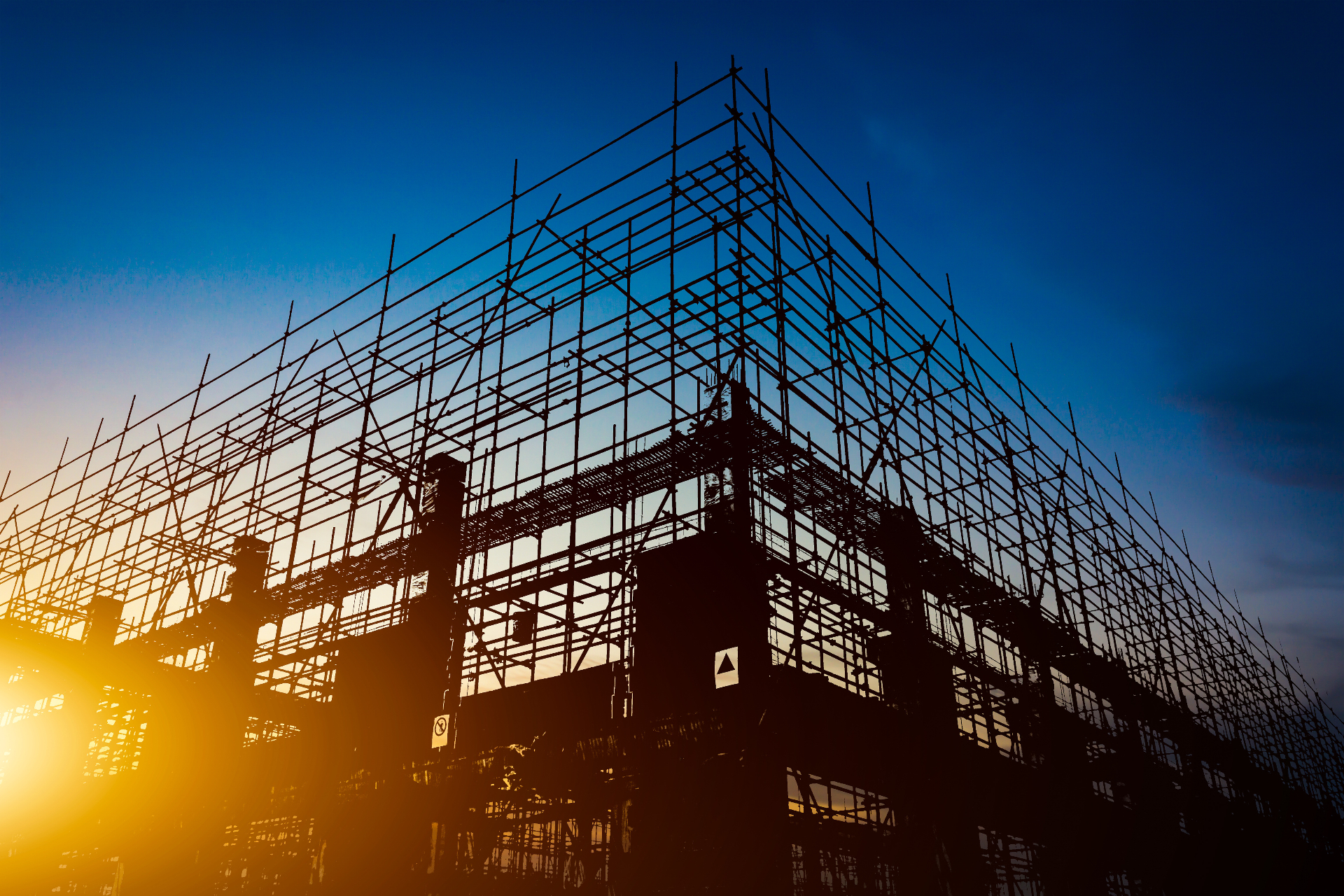 Crane operator scaffolding silhouette against an industrial sunset on a working jobsite